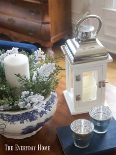 a candle and some tea lights are on a table with flowers in a blue and white vase