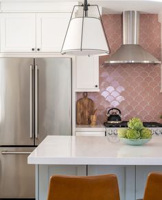 a kitchen with two brown chairs next to an island and stainless steel refrigerator freezer