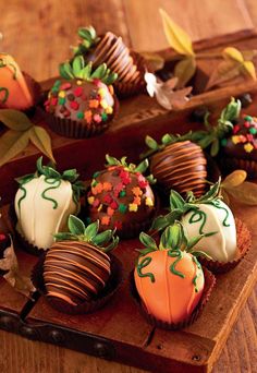 chocolate covered strawberries are arranged on a wooden platter with leaves and pumpkins