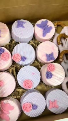 a box filled with lots of cupcakes covered in frosting and pink icing