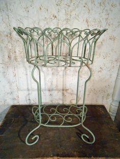 there is a wire basket on top of a wooden table in front of a wall