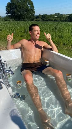 a man sitting in a bathtub with his feet up and one hand raised above the water