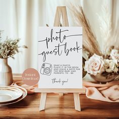 a wooden easel with a sign that says, photo guest booth on it and flowers in the background