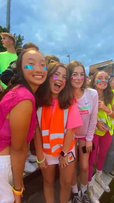 three girls with face paint standing next to each other in front of a group of people