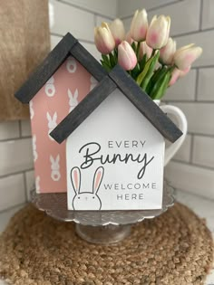 there is a small house with flowers in it on top of a cake plate that says, every bunny welcome here