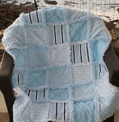 a blanket that is on top of a chair in front of some grass and dirt