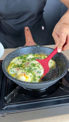 a person cooking food in a pan on top of the stove with a red spatula