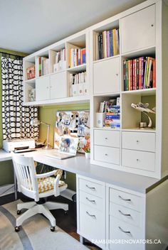 a white desk sitting under a window next to a book shelf filled with lots of books