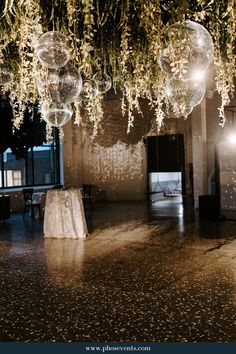 the ceiling is decorated with hanging glass balls and greenery in an old building at night