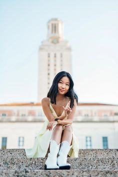 a woman sitting on the steps in front of a building with tall buildings behind her