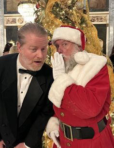 two men dressed up as santa clause and one is holding his hand to his face