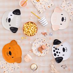 an assortment of animal themed plates and napkins on a table with utensils