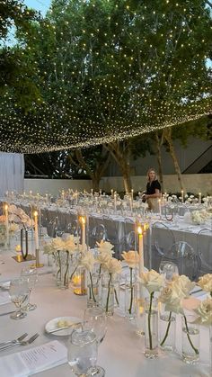 the tables are set up with clear vases filled with white flowers and lit candles