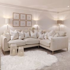 a living room filled with white furniture and pillows on top of a shaggy area rug