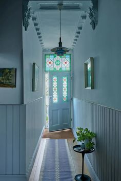 a hallway with a blue door and stained glass window on the side wall above it