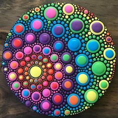 a colorful painting on a wooden surface with circles and dots in the center, as well as colors