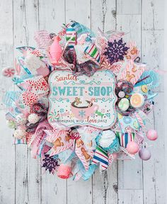 a wreath made out of fabric and buttons on a white wooden background with the words sweet shop