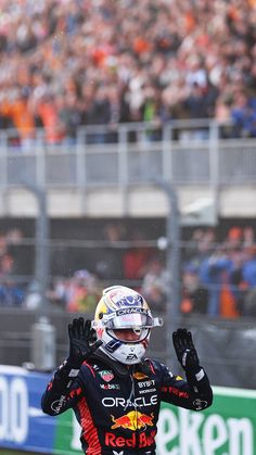 a red bull driver waves to the crowd as he makes his way down the track