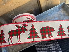 a red and green plaid ribbon with moose, pine trees and snowflakes on it