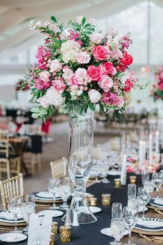 a tall vase filled with pink and white flowers on top of a black table cloth