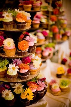 cupcakes are stacked on top of each other and decorated with colorful flower petals