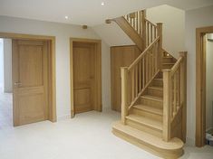 an empty living room with stairs leading up to the second floor and another open door