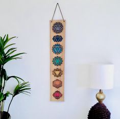 a wooden wall hanging with seven chakras on it next to a potted plant