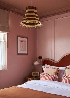 a bedroom with pink walls and striped pillows