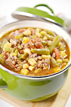 a close up of a bowl of soup on a wooden board with a spoon in it