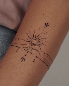 a woman's arm with a sun and arrows tattoo on the left side of her arm