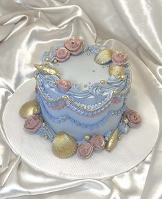 a blue and gold decorated cake sitting on top of a white cloth covered tablecloth