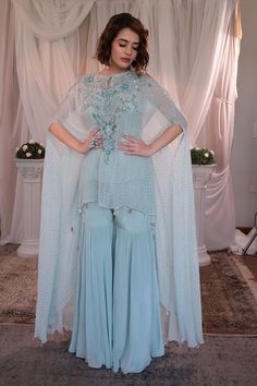 Blue asymmetric kaftan featuring mukaish embellishment. Paired with matching sharara pant. - Aza Fashions Traditional Dress With Sheer Dupatta And Cape Sleeves, Traditional Sharara With Cape Sleeves, Party Sets With Dabka Work And Cape Sleeves, Semi-stitched Light Blue Dress With Intricate Embroidery, Light Blue Semi-stitched Dress With Intricate Embroidery, Blue Kaftan With Zari Work For Party, Blue Zari Work Kaftan For Party, Party Sharara With Chikankari Embroidery In Traditional Drape, Traditional Kurta With Sheer Dupatta And Cape Sleeves