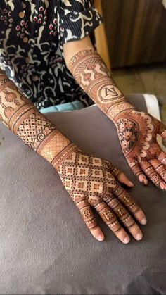 a woman with henna tattoos on her hands and hand is sitting at a table