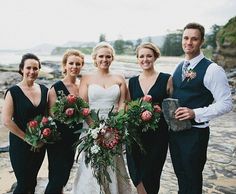 a group of people standing next to each other on a beach with flowers in their hands