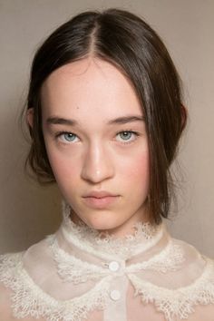 a woman with blue eyes wearing a white collared shirt and looking at the camera