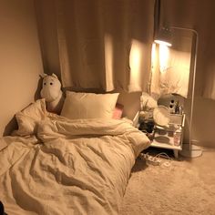 an unmade bed with white sheets, pillows and a stuffed animal on the side