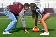 two people bending over to pick up an orange football