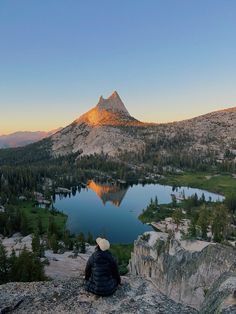 a person sitting on top of a mountain overlooking a lake