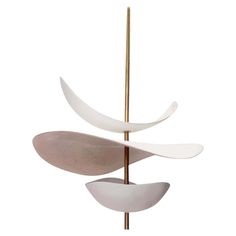 an abstract sculpture with three different shapes on it's sides and a gold pole