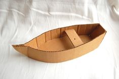 an empty cardboard boat sitting on top of a white bed sheet with the lid open