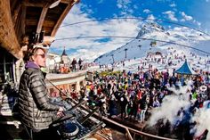 a crowd of people standing on top of a snow covered mountain next to a dj's turntable