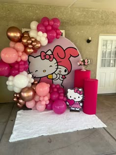 a hello kitty balloon arch with pink, gold and white balloons