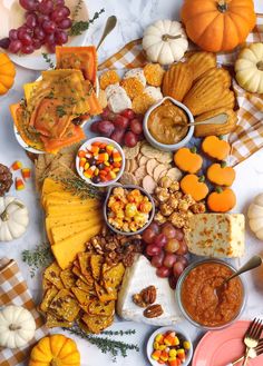 a table topped with lots of different types of food next to pumpkins and gourds