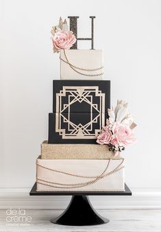 a three tiered wedding cake with flowers on top and the letter h spelled out