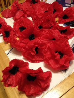 some red flowers are on a table and one is in the process of being made