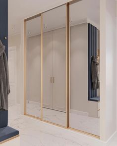 an open closet with mirrored doors and coat racks on the wall, along with two coats hanging from hooks