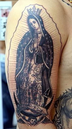 a man with a tattoo on his arm and shoulder has a virgin mary in the center