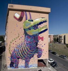 a large mural on the side of a building with a dinosaur painted on it's side