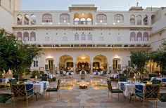 an outdoor dining area with tables and chairs in front of a large, white building