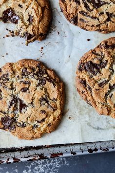 four chocolate chip cookies on a baking sheet